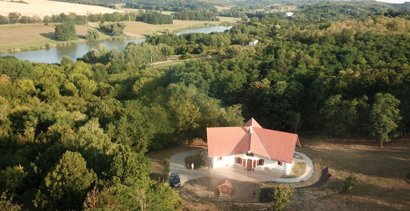 A Zselici Bagoly Vendégház madártávlatból, háttérben a tóval és a Zselic erdeivel